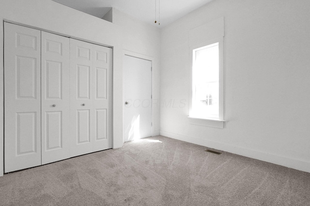 unfurnished bedroom featuring baseboards, a closet, visible vents, and carpet flooring