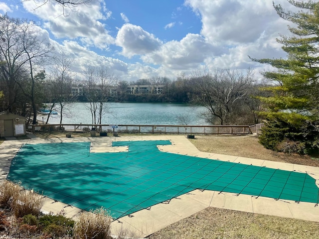 community pool with a patio, fence, a water view, and an outdoor structure