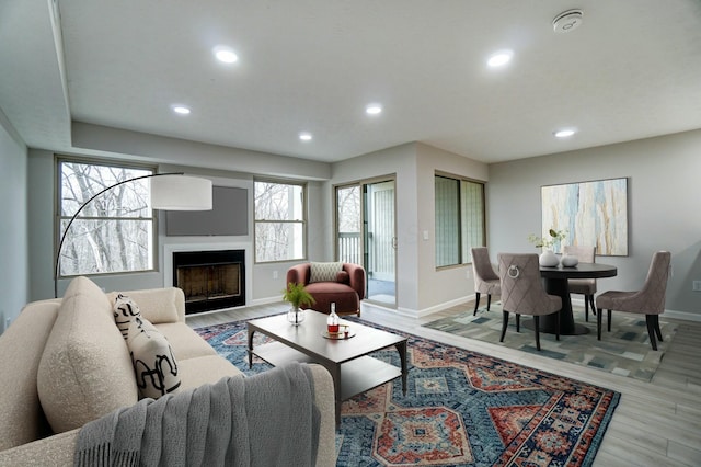 living room featuring a fireplace, recessed lighting, light wood-type flooring, and baseboards