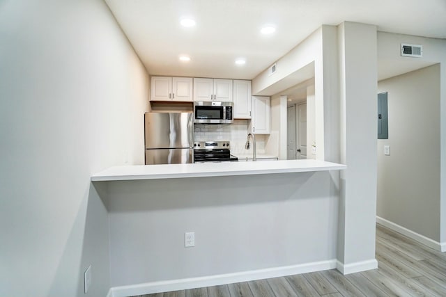 kitchen featuring visible vents, a peninsula, white cabinets, appliances with stainless steel finishes, and tasteful backsplash