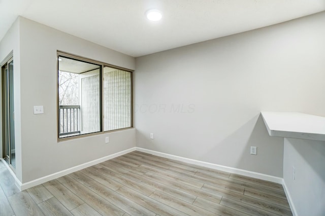 spare room featuring light wood-style floors and baseboards