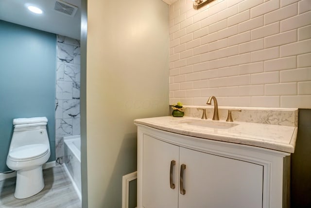 full bath with visible vents, toilet, bathing tub / shower combination, wood finished floors, and vanity