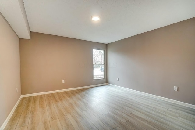 unfurnished room featuring baseboards and light wood finished floors