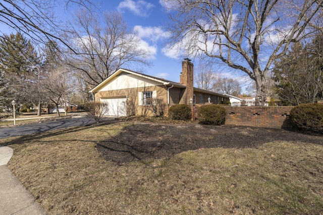 view of property exterior featuring driveway, a chimney, an attached garage, fence, and brick siding