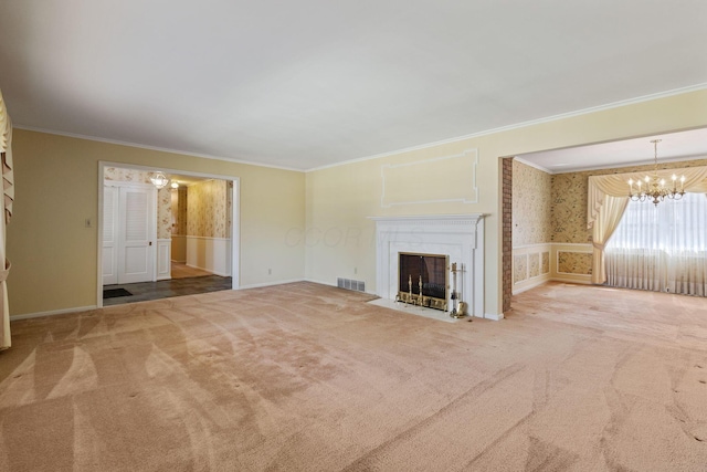 unfurnished living room with visible vents, a fireplace with flush hearth, crown molding, carpet floors, and a chandelier