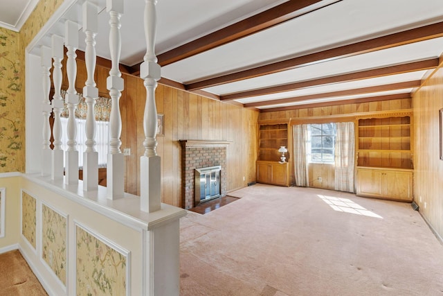 unfurnished living room with a brick fireplace, wooden walls, beam ceiling, and carpet flooring