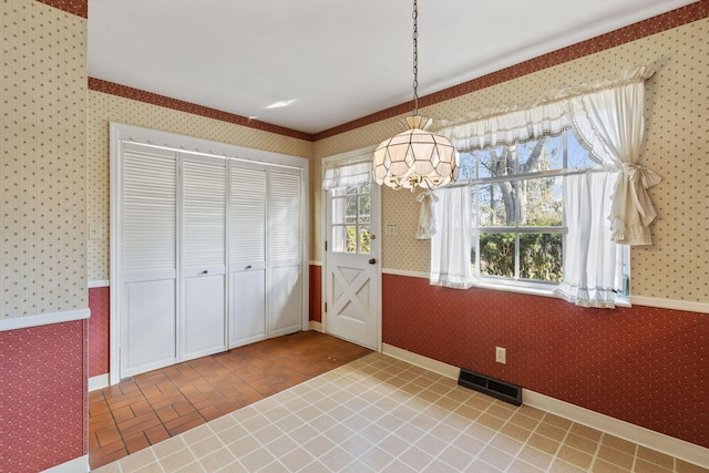 unfurnished dining area featuring baseboards, brick floor, visible vents, and wallpapered walls