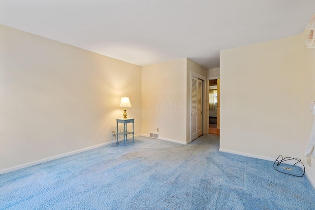 unfurnished room with carpet floors, visible vents, and baseboards