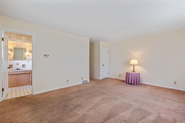 spare room featuring light colored carpet, visible vents, and baseboards