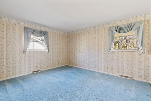 carpeted empty room with baseboards, visible vents, and wallpapered walls