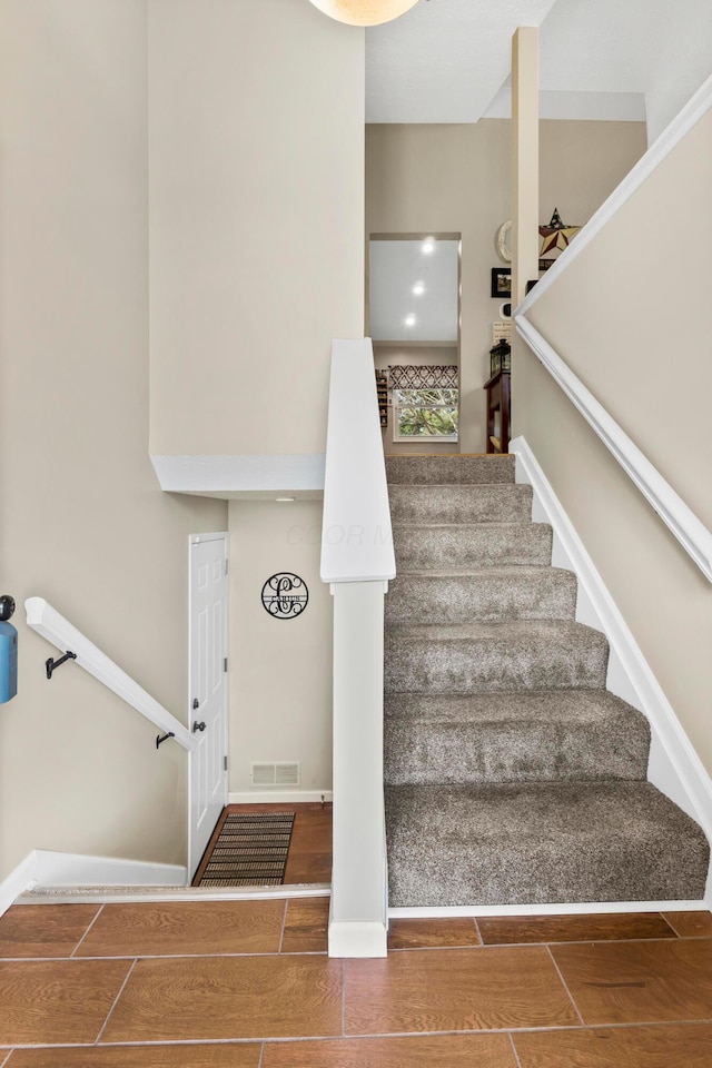 stairway with baseboards, visible vents, and wood finish floors