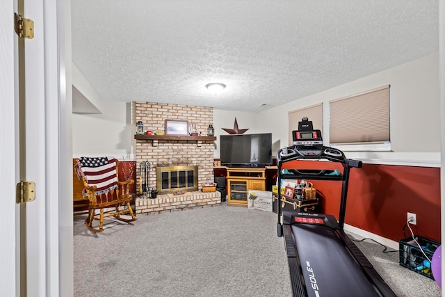 exercise room with a brick fireplace, a textured ceiling, and carpet flooring