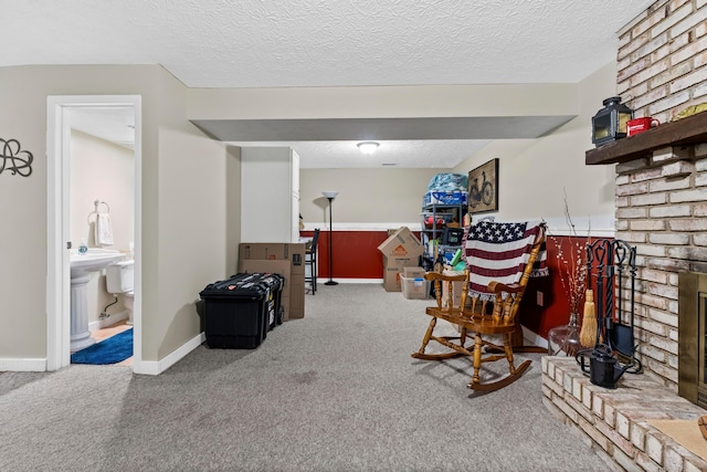 sitting room featuring carpet, baseboards, and a textured ceiling