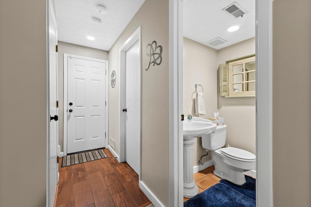 bathroom featuring toilet, wood finished floors, visible vents, and baseboards