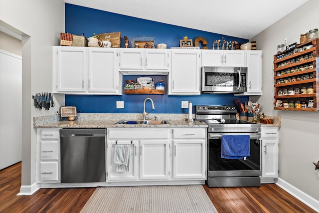 kitchen with appliances with stainless steel finishes, white cabinets, a sink, and dark wood-style floors