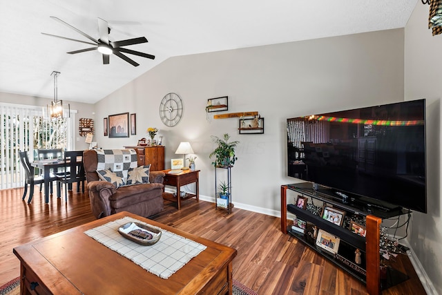 living room featuring ceiling fan with notable chandelier, lofted ceiling, baseboards, and wood finished floors