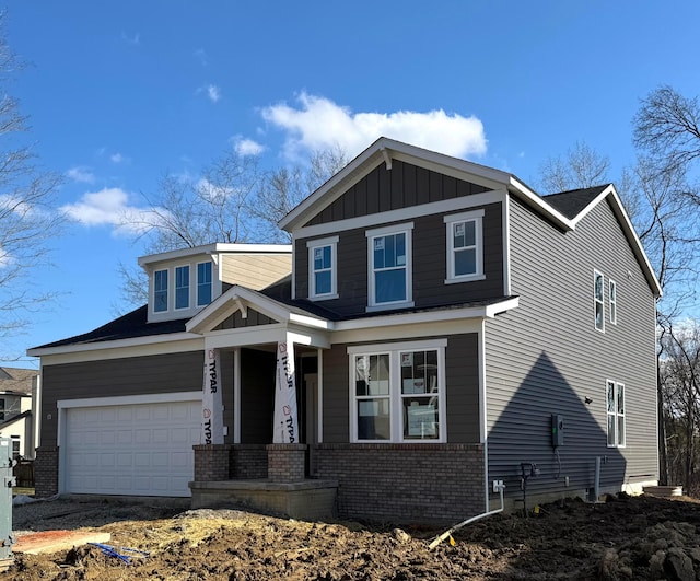 view of front of property with board and batten siding, covered porch, brick siding, and an attached garage