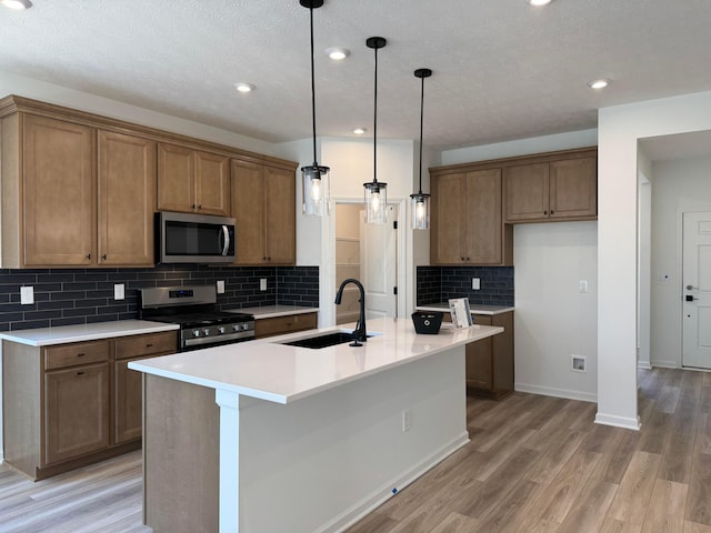 kitchen featuring brown cabinets, appliances with stainless steel finishes, a sink, and light wood-style floors