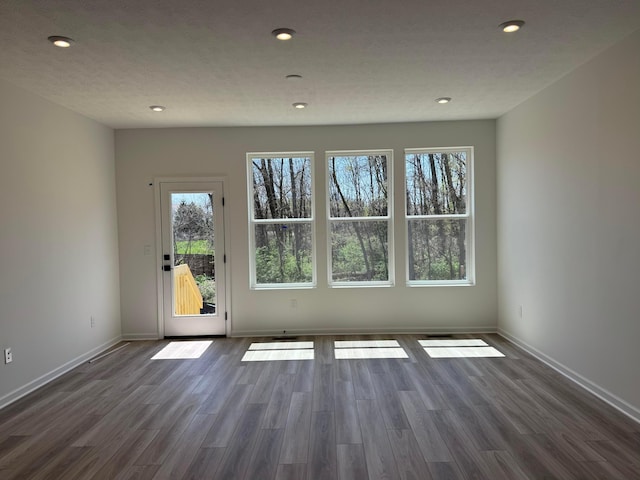 interior space with baseboards, recessed lighting, wood finished floors, and plenty of natural light