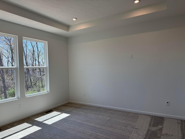 empty room with recessed lighting, a raised ceiling, visible vents, carpet floors, and baseboards