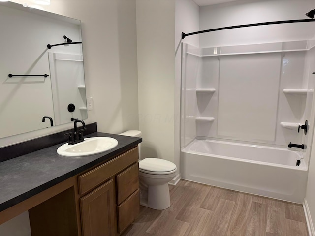 bathroom featuring wood finished floors, toilet, vanity, and bathing tub / shower combination