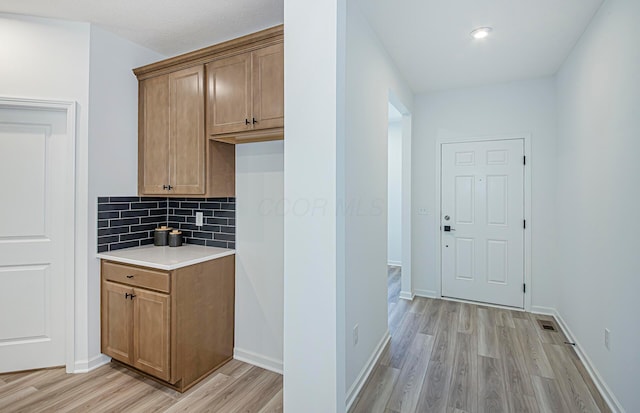 603 Mill Stone Dr Lot 2257, Sunbury, OH 43074 - kitchen with light wood finished floors, light countertops, decorative backsplash, baseboards, and brown cabinetry