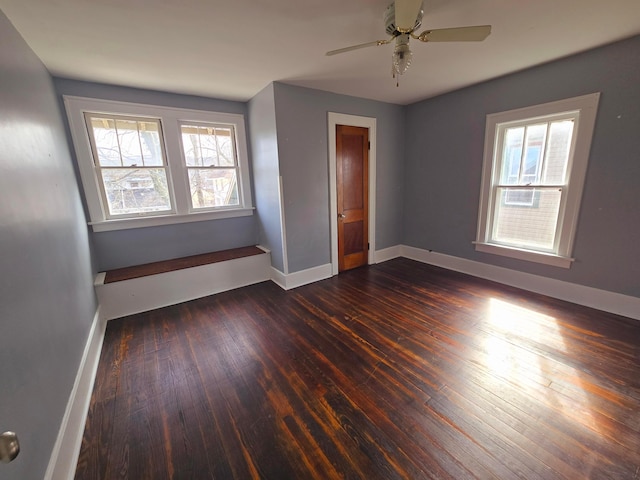 spare room featuring a ceiling fan, baseboards, and dark wood-type flooring