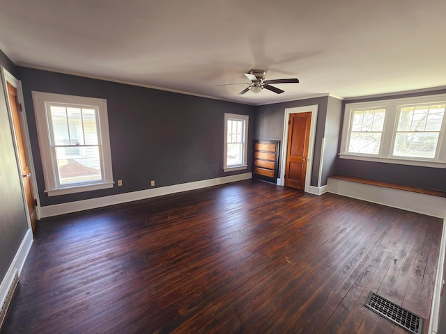 unfurnished bedroom with baseboards, visible vents, a ceiling fan, dark wood-style floors, and crown molding