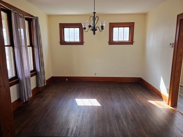 unfurnished room with dark wood-style floors, baseboards, and a notable chandelier