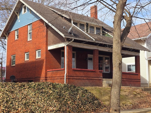 view of property exterior featuring roof with shingles, a chimney, and brick siding