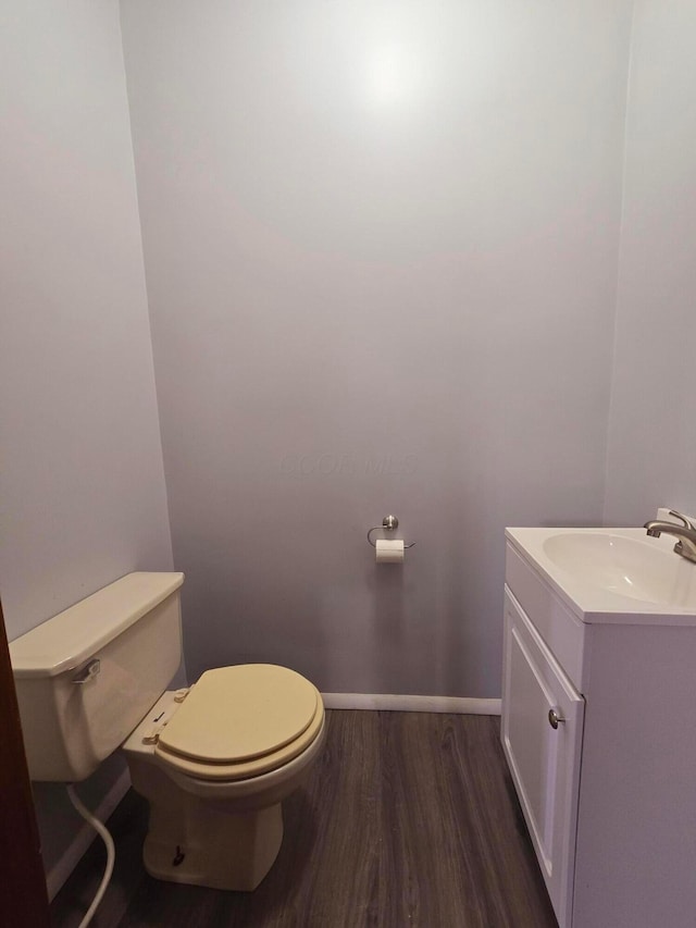 bathroom with toilet, baseboards, wood finished floors, and vanity