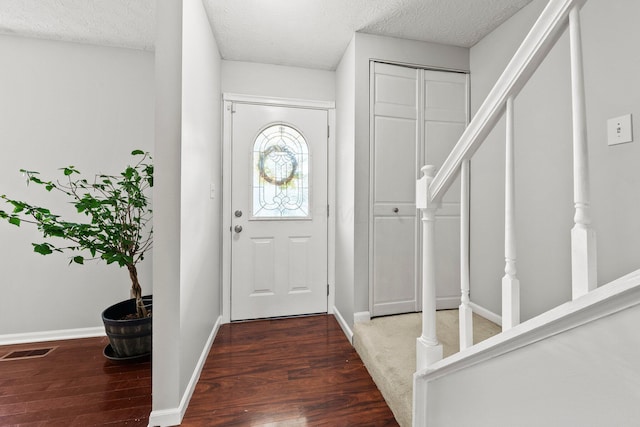 entrance foyer featuring visible vents, baseboards, wood finished floors, and stairway