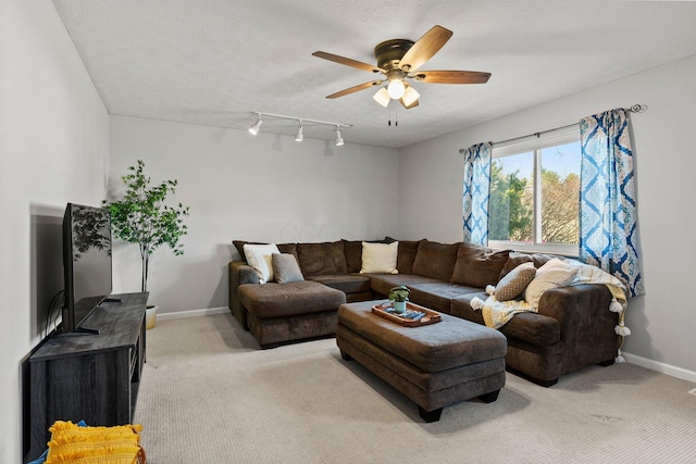 living area featuring baseboards, light colored carpet, a textured ceiling, and a ceiling fan