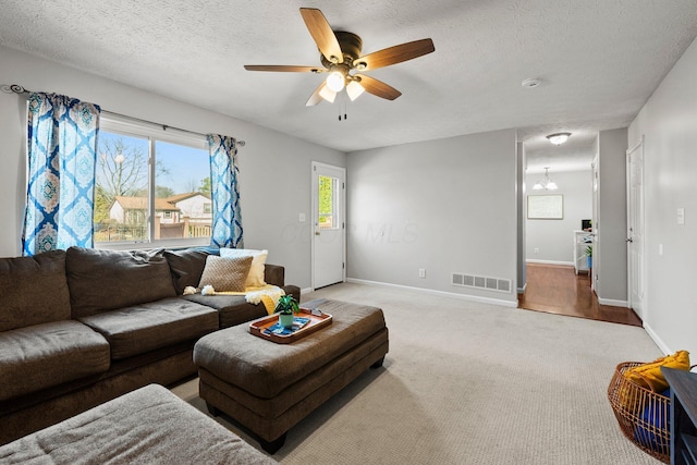 living area with a ceiling fan, baseboards, carpet, visible vents, and a textured ceiling