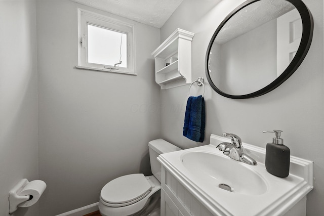 bathroom featuring a textured ceiling, toilet, vanity, and baseboards