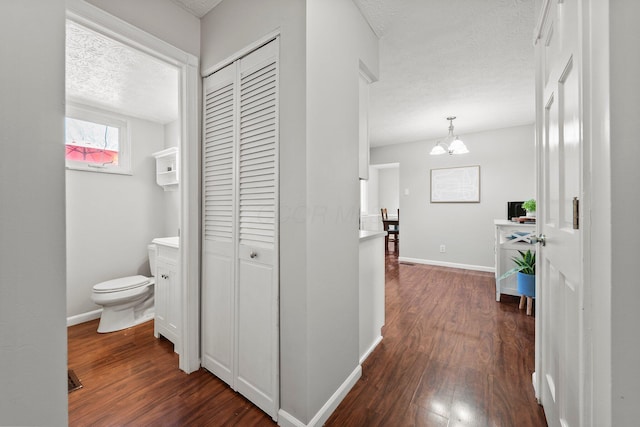 corridor featuring dark wood-style floors, a textured ceiling, and baseboards