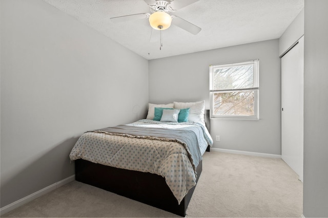 bedroom with carpet flooring, a textured ceiling, baseboards, and a ceiling fan