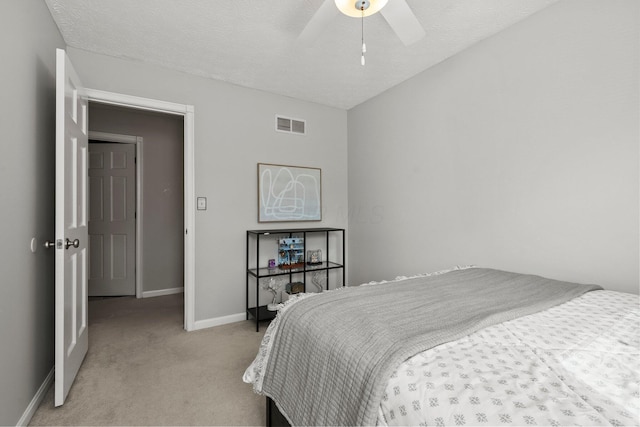 bedroom with visible vents, a textured ceiling, baseboards, light colored carpet, and ceiling fan