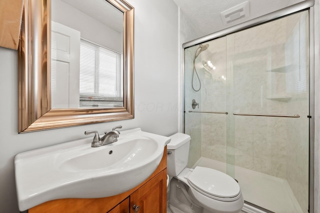 full bath with vanity, visible vents, a stall shower, a textured ceiling, and toilet