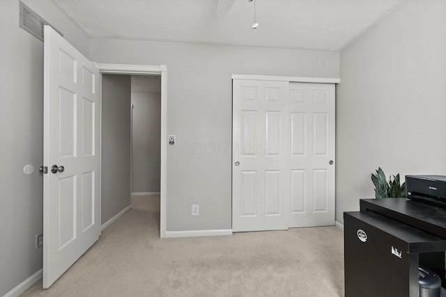 bedroom featuring visible vents, baseboards, light colored carpet, and a closet