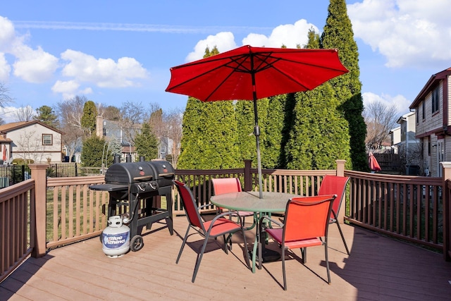 wooden terrace with outdoor dining space, a grill, and fence