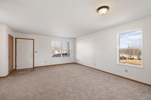 unfurnished room featuring a textured ceiling, carpet flooring, and baseboards