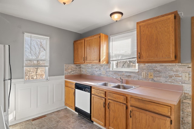 kitchen featuring white appliances, visible vents, a wainscoted wall, light countertops, and a sink