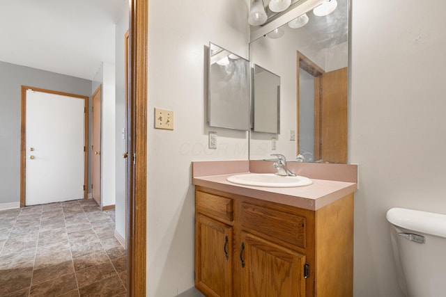 bathroom with toilet, baseboards, and vanity