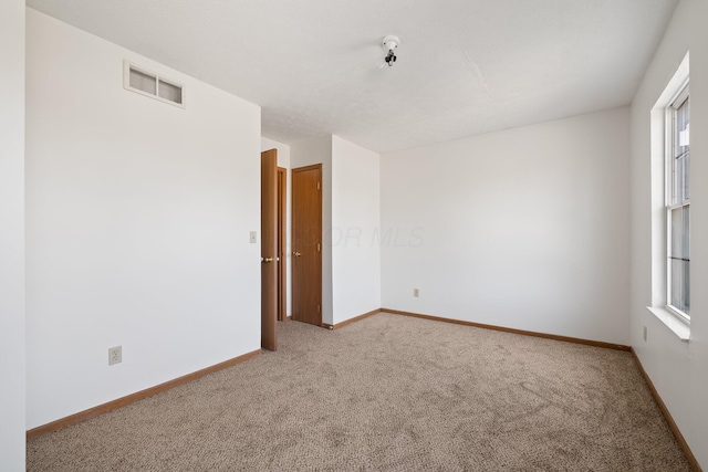 spare room with a healthy amount of sunlight, baseboards, and visible vents