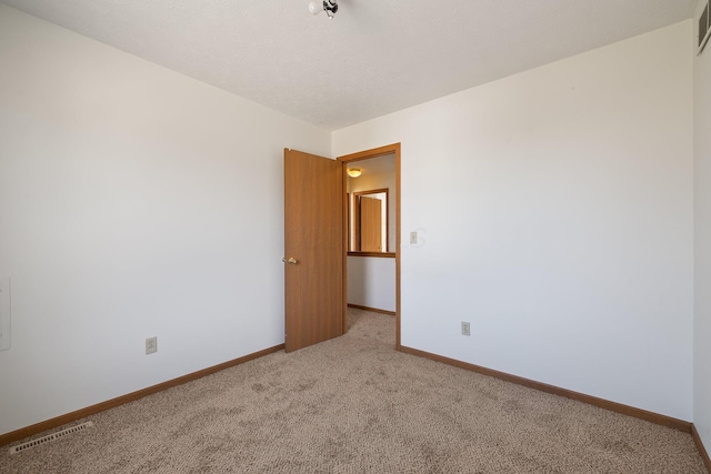 carpeted spare room with visible vents and baseboards