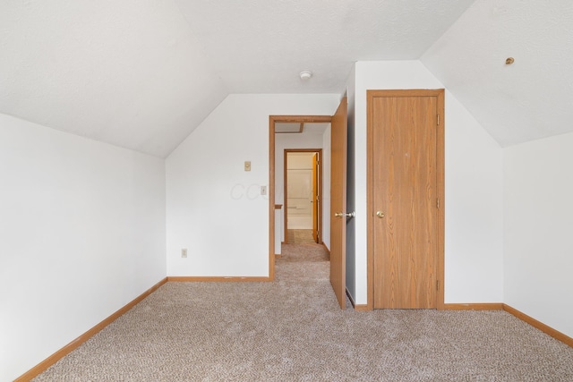 additional living space featuring lofted ceiling, a textured ceiling, and baseboards