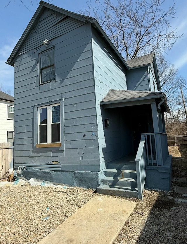 view of home's exterior with a shingled roof and fence