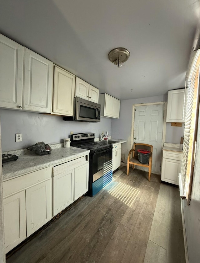 kitchen featuring electric stove, light countertops, stainless steel microwave, dark wood-type flooring, and white cabinetry