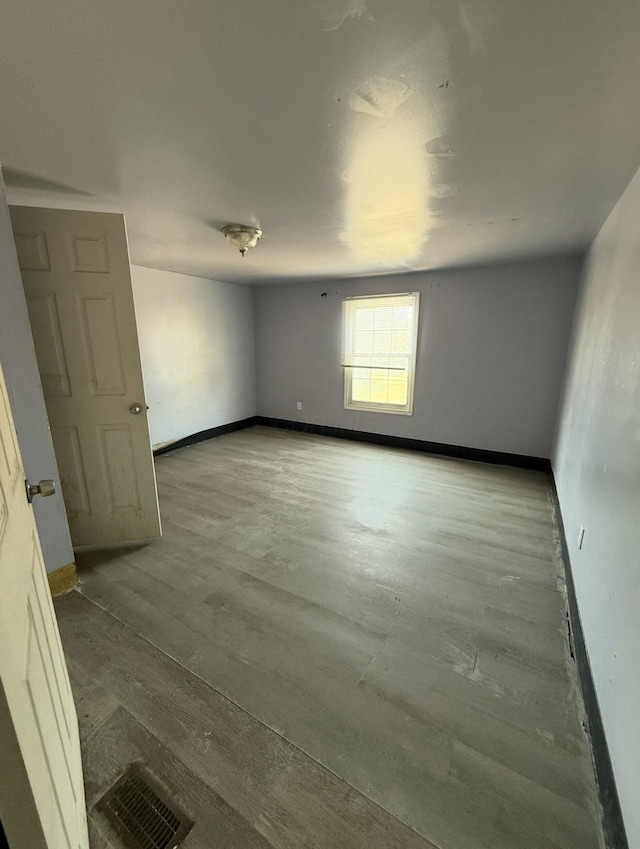 empty room featuring visible vents, baseboards, and wood finished floors